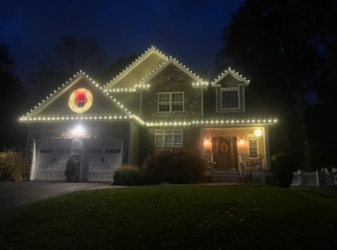 Two-story home outlined with warm white holiday lights